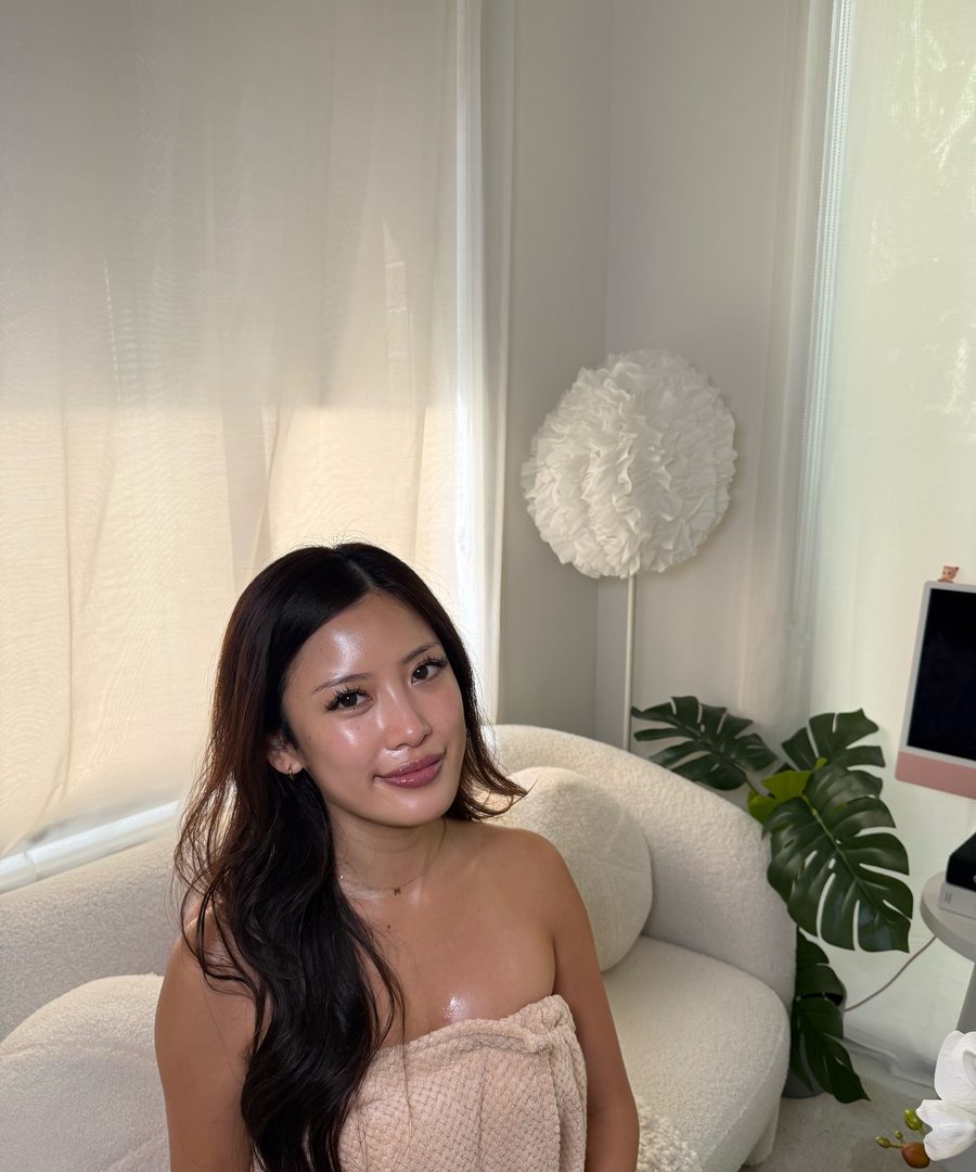 A client with dewy glass skin wrapped in a spa towel