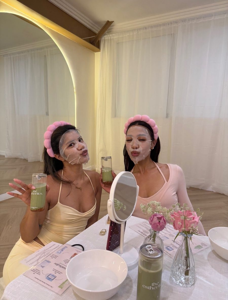 Two clients in sheet masks holding the esthertics. strawberry matcha cans at a Sunday Reset event